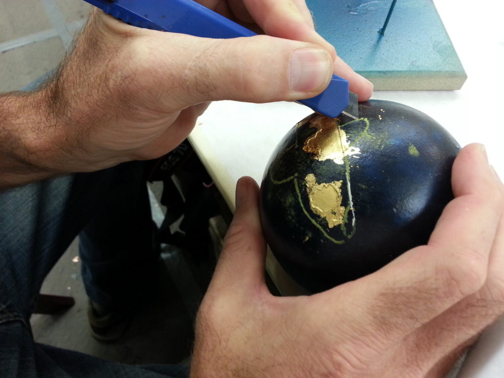 Student working on applying metal leaf to a sphere.