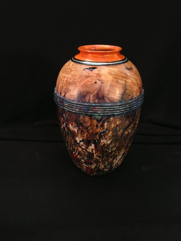 "Desert Urn" is the title of this 81/2" tall x 51/2" diameter hollow vessel I turned. It combines silver inlay into the pernambuco and ebony rim at the top. I gilded the lower body of the vessel with silver leaf and did a patina finish over it.